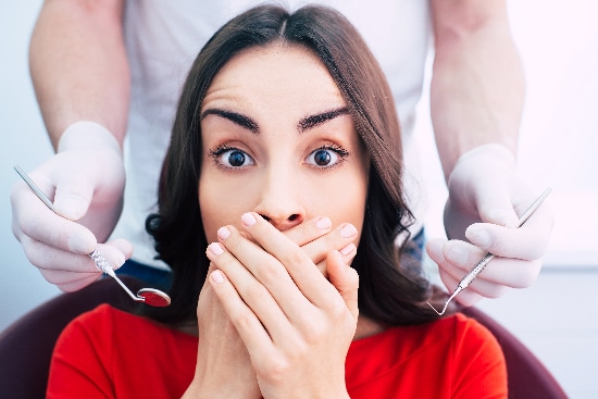 young woman covering here mouth to avoid dentist, in need of professional dental sedation to ease anxiety