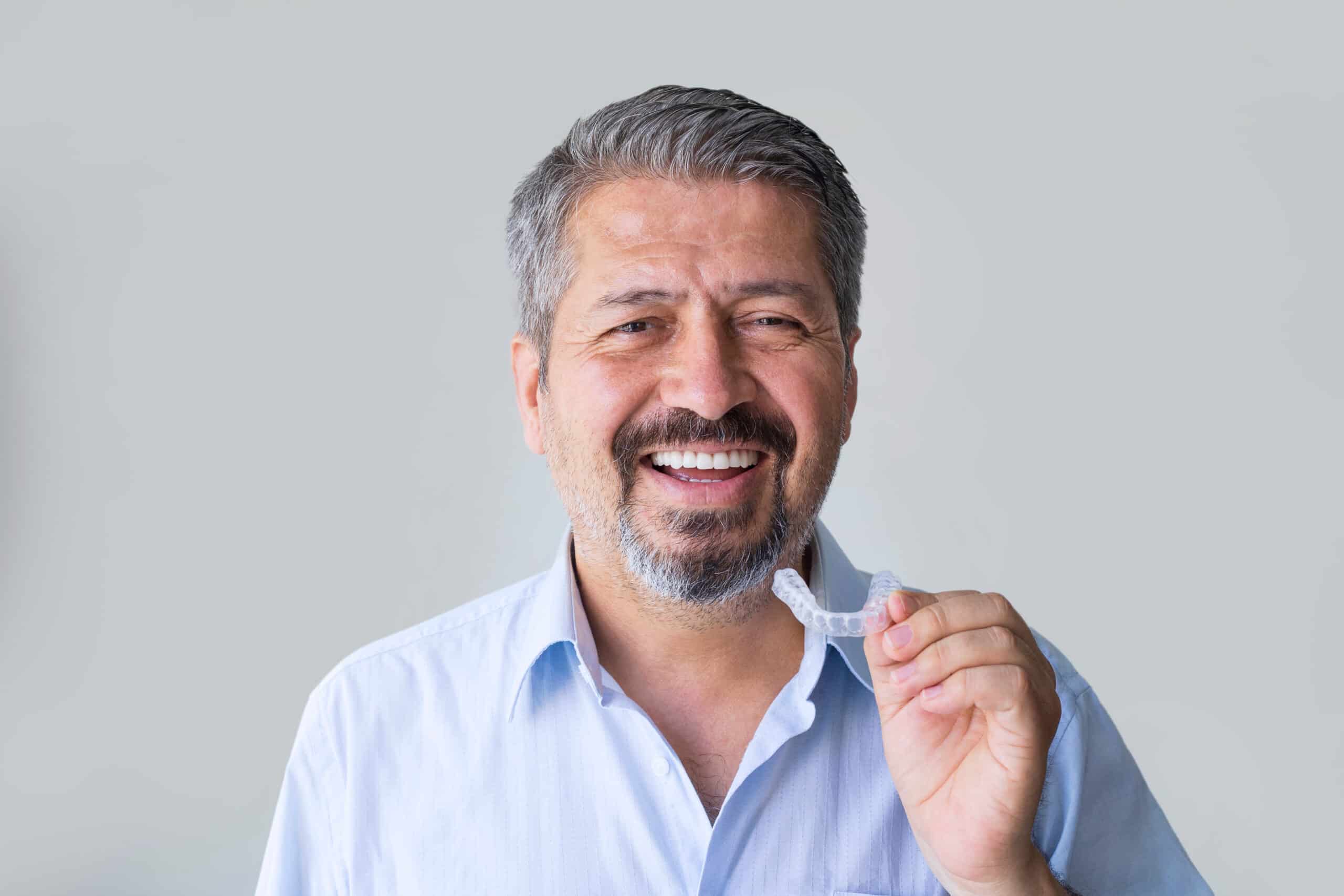 Close-up of a Adult Man Putting Transparent Aligner on His Teeth
