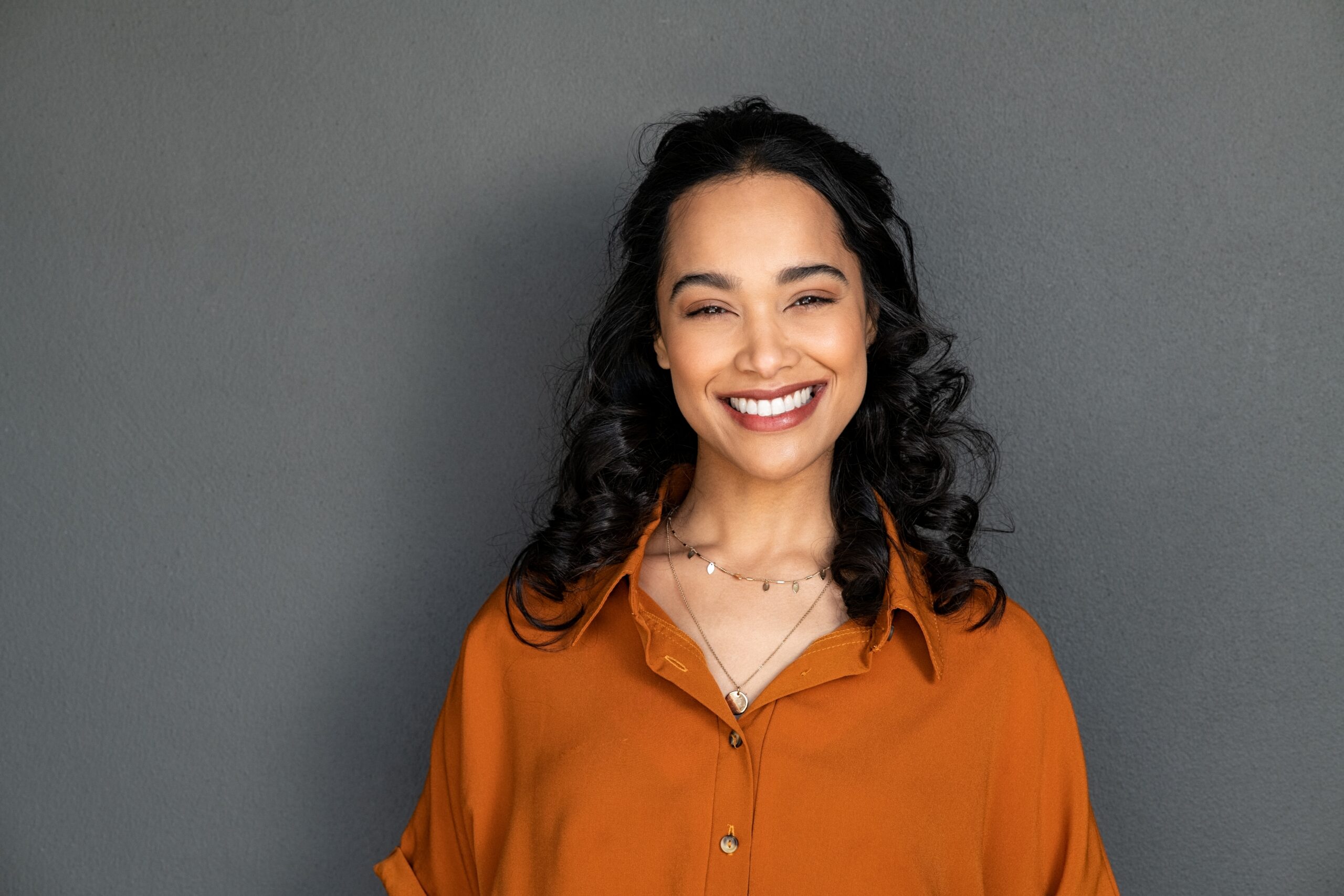 young woman showing perfect white smile against a grey backdrop