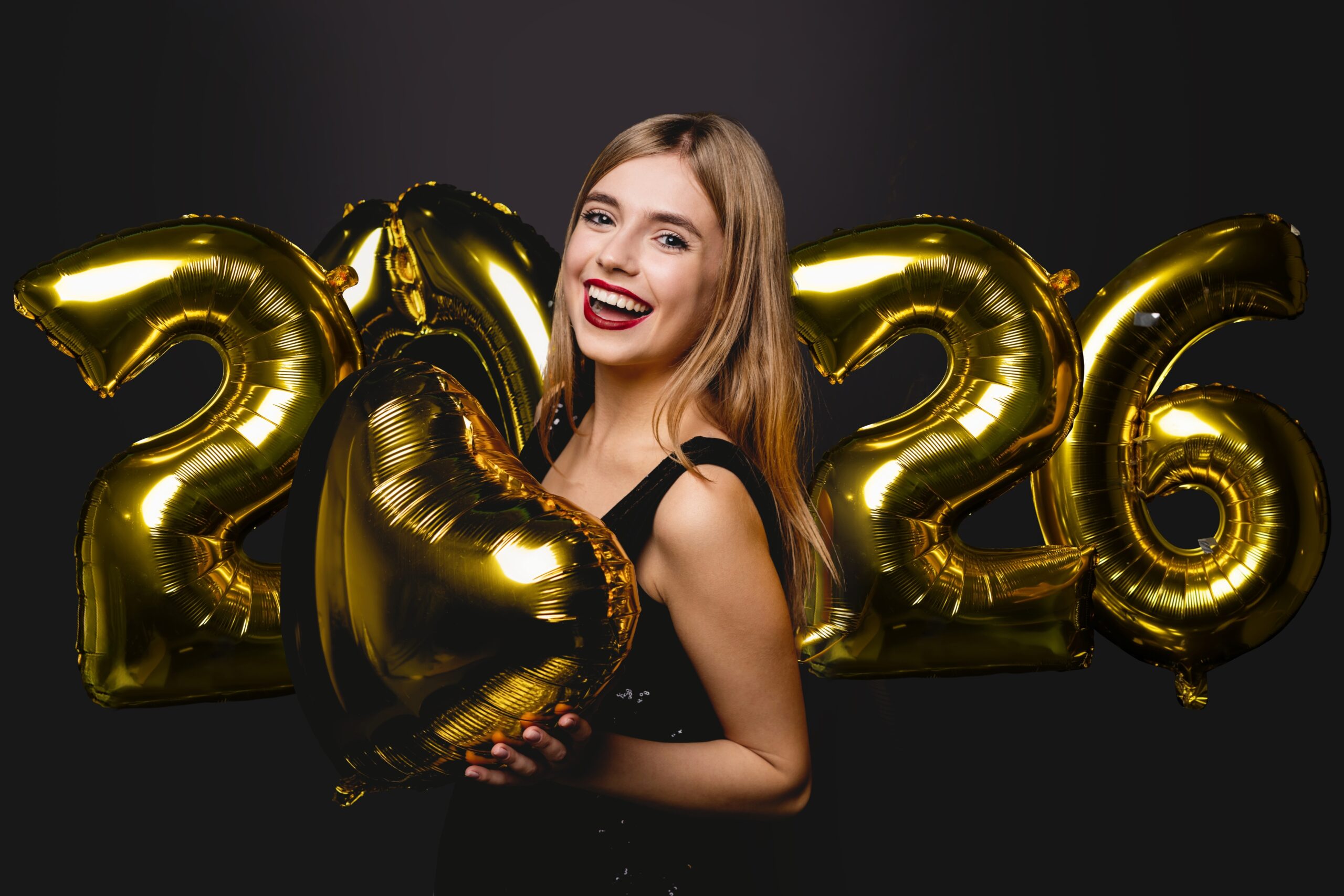 young woman smiling holding 2026 balloons, perfect white teeth