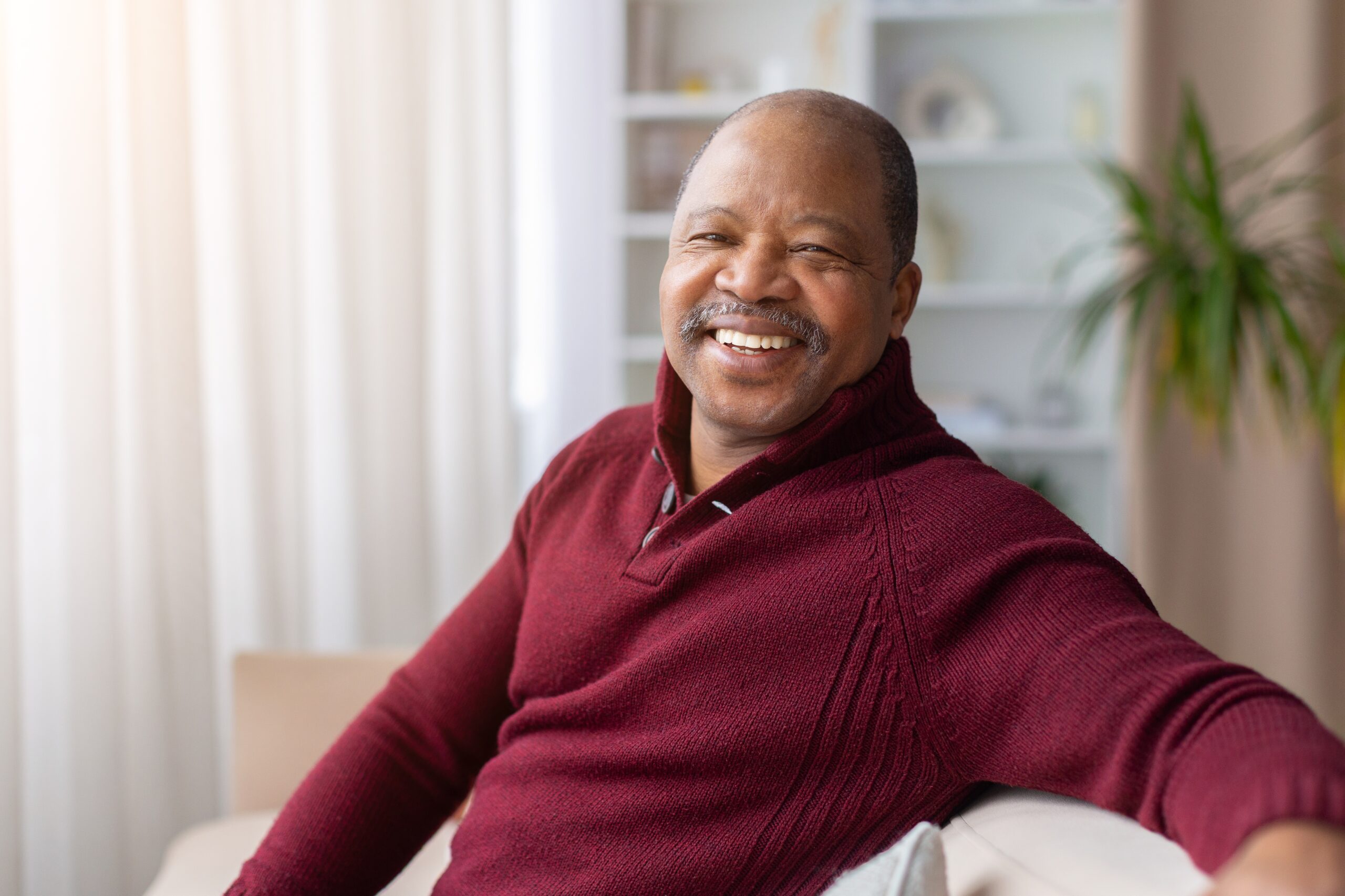 smiling older man on couch, new dental veneers